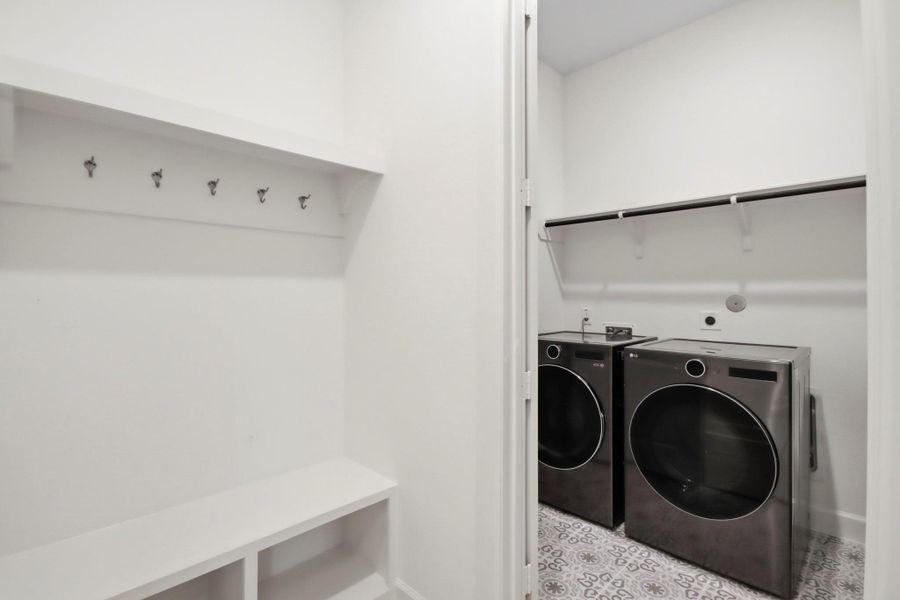 Modern laundry room with sleek appliances, ample shelving, and stylish tile flooring for convenience and functionality.