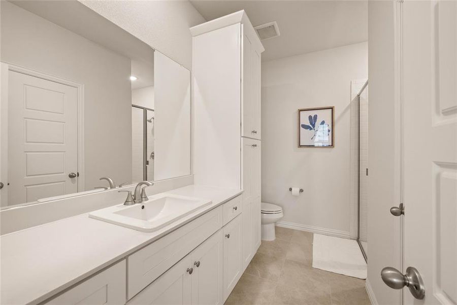 Bathroom with vanity, toilet, a shower with shower door, and tile patterned flooring