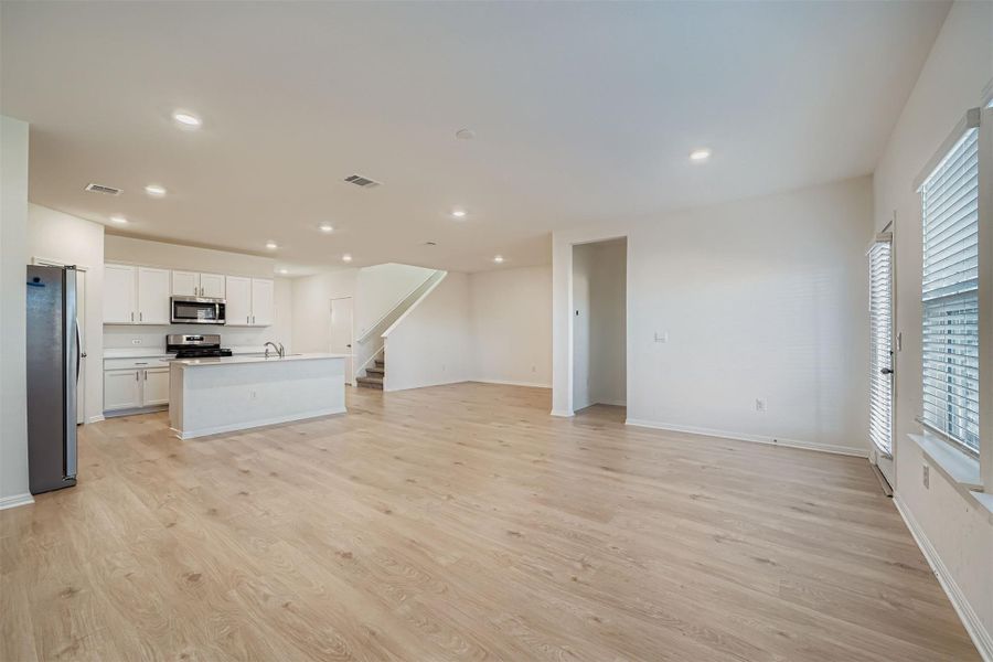 Unfurnished living room featuring light wood-type flooring, recessed lighting, and stairs