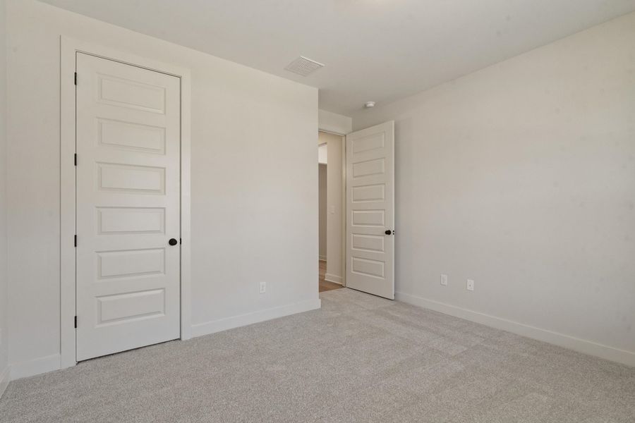 Light-colored carpeting, white interior doors with matte black hardware, and light neutral wall paint Light-colored carpeting, white interior doors with matte black hardware, and light neutral wall paint