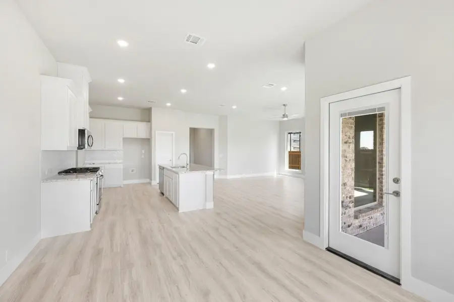 Open-concept kitchen and living area with white cabinets, center island, and light wood floors