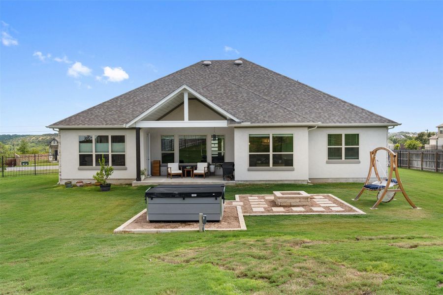 Rear view of property featuring stucco siding, a fenced backyard, a patio, and a shingled roof