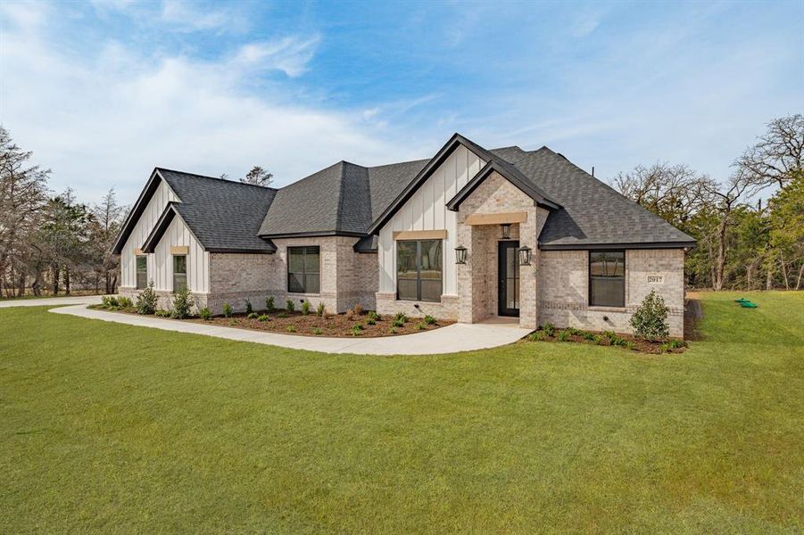 View of front of house featuring board and batten siding, a front lawn, brick siding, and roof with shingles View of front of house featuring board and batten siding, a front lawn, brick siding, and roof with shingles