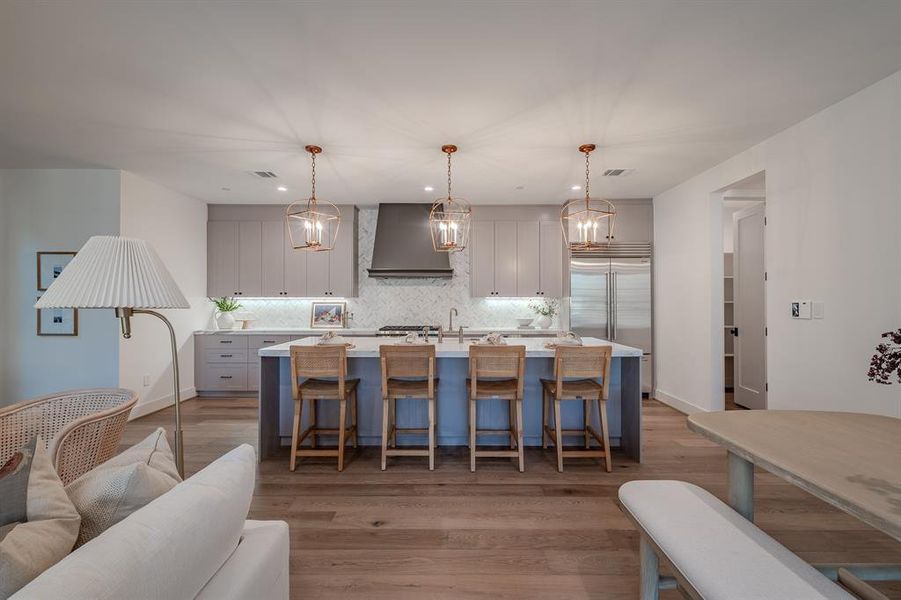 Kitchen with gray cabinetry, a kitchen bar, backsplash, hanging light fixtures, and recessed lighting Kitchen with gray cabinetry, a kitchen bar, backsplash, hanging light fixtures, and recessed lighting