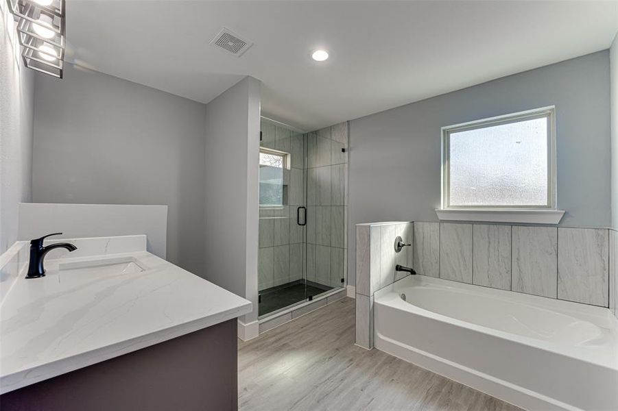 Bathroom with hardwood / wood-style flooring, vanity, and shower with separate bathtub