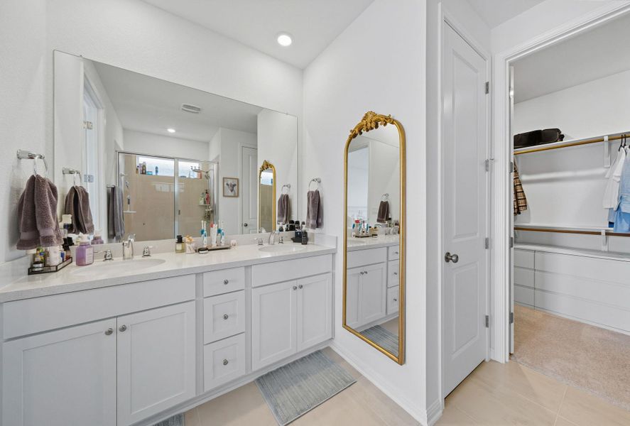 Bathroom with a shower stall, double vanity, a spacious closet, light tile patterned floors, and recessed lighting Bathroom with a shower stall, double vanity, a spacious closet, light tile patterned floors, and recessed lighting