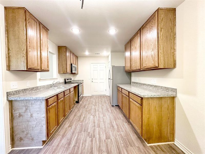 Kitchen with appliances with stainless steel finishes, sink, and light hardwood / wood-style flooring