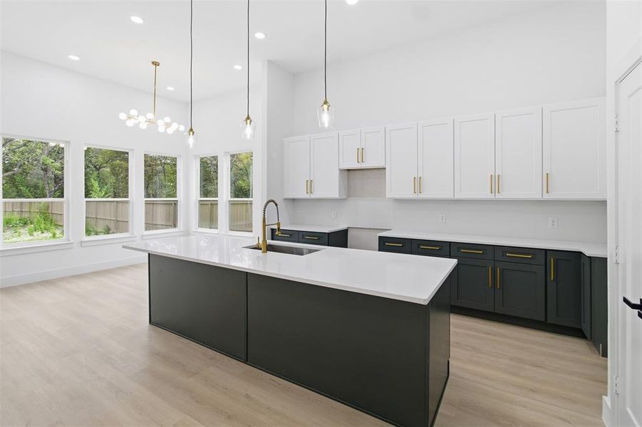 Kitchen with white cabinetry, recessed lighting, a center island with sink, pendant lighting, and light wood finished floors