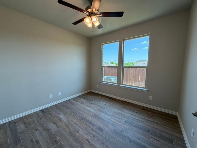 Room featuring wood-finish flooring, neutral wall tones, and white baseboards