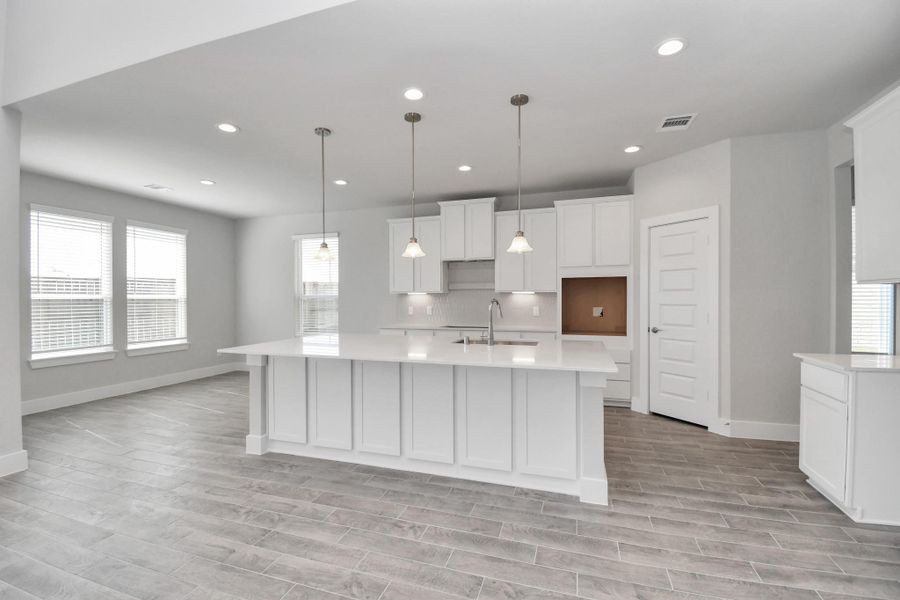 The kitchen is a culinary haven, featuring granite countertops, a tile backsplash, stainless steel appliances, 42” upper cabinets, and undercabinet lighting. Sample photo of completed home with similar floor plan. Actual colors and selections may vary.