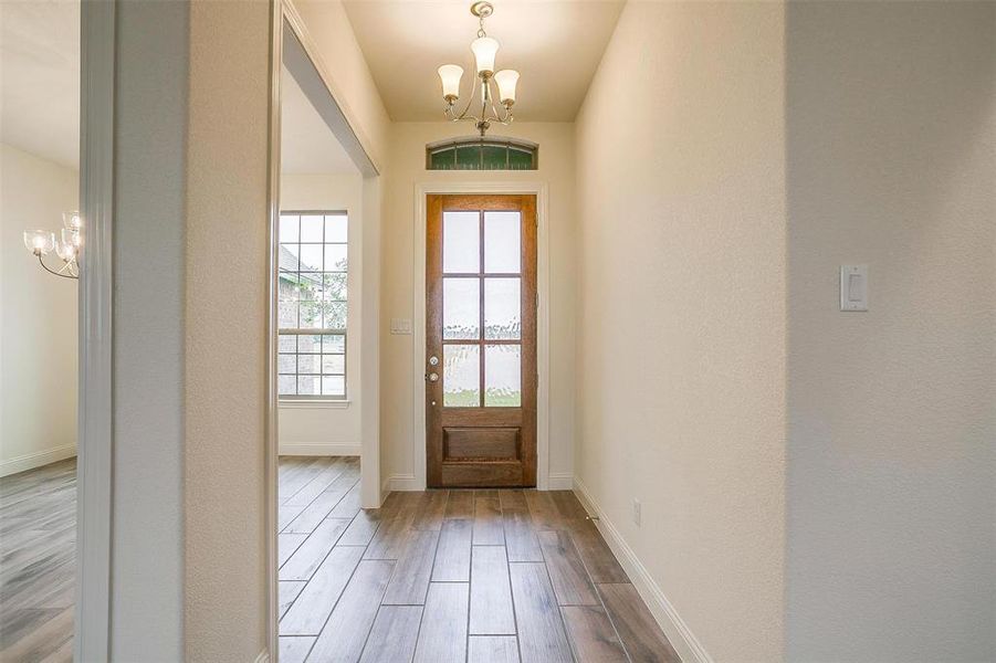 Doorway to outside featuring a chandelier and light wood-type flooring