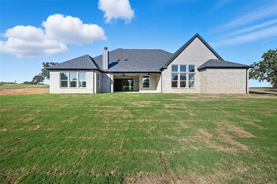 Back of house with brick siding, a patio area, and a lawn Back of house with brick siding, a patio area, and a lawn