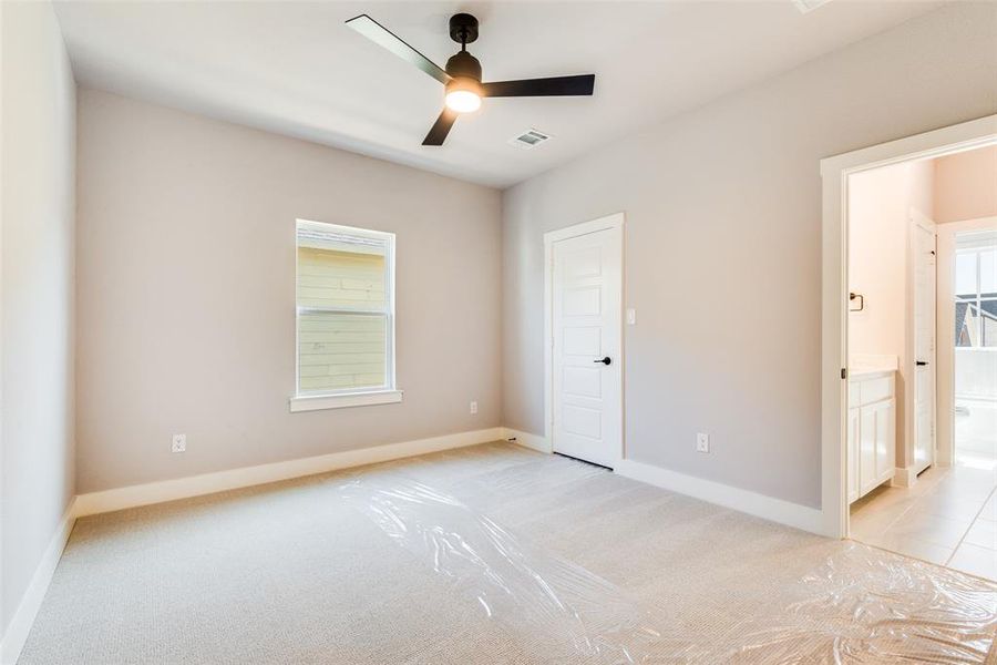 Unfurnished bedroom featuring light colored carpet, multiple windows, and ceiling fan