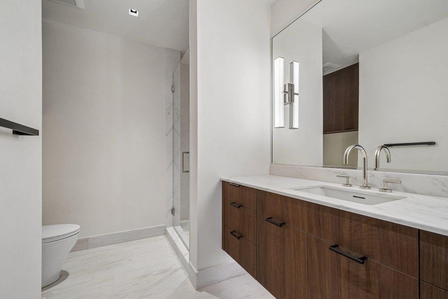 Clean lines and a warm wood vanity define this modern bathroom with a glass shower. Clean lines and a warm wood vanity define this modern bathroom with a glass shower.