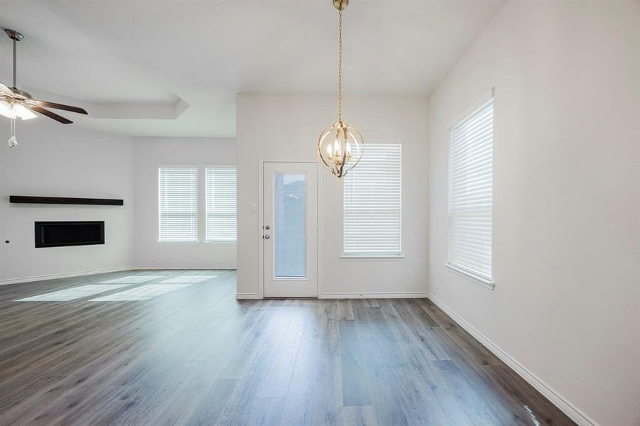 Unfurnished living room with dark hardwood / wood-style flooring and ceiling fan with notable chandelier