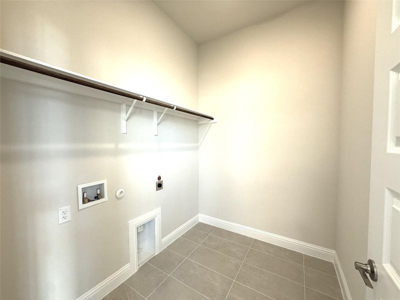 Washroom with electric dryer hookup, hookup for a gas dryer, washer hookup, and tile patterned floors