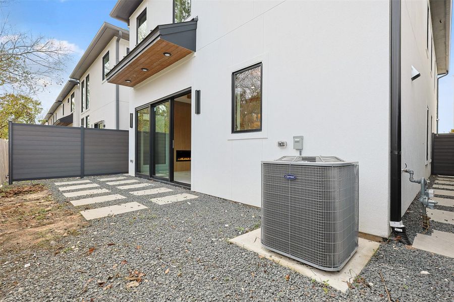 The outdoor space consists of a low-maintenance gravel yard with geometric concrete pavers leading to a large sliding glass door.