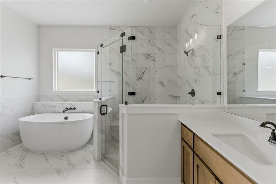 Bathroom with a marble finish shower, vanity, a freestanding bath, tile walls, and light marble finish floors