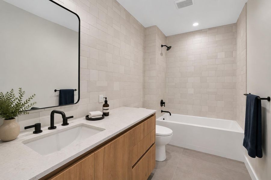 A well-lit bathroom features a spacious vanity with an integrated sink and a sleek, modern tub-shower combination.