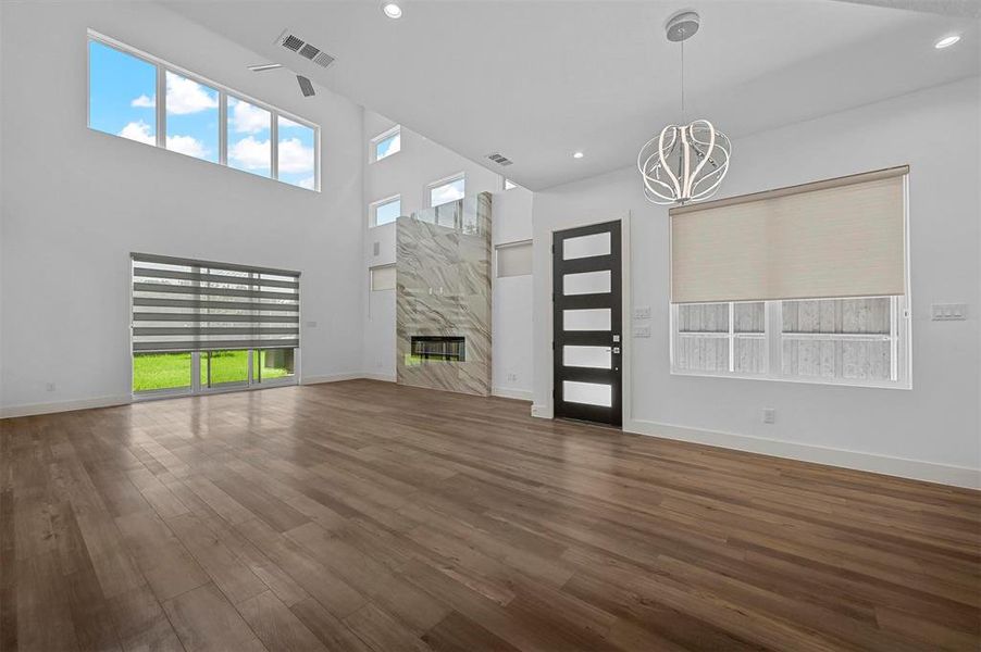 Unfurnished living room featuring a high ceiling, a healthy amount of sunlight, a fireplace, and dark hardwood / wood-style flooring