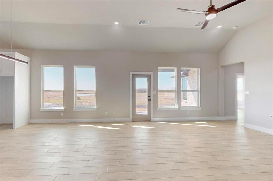 Unfurnished living room with visible vents, lofted ceiling, a healthy amount of sunlight, and ceiling fan