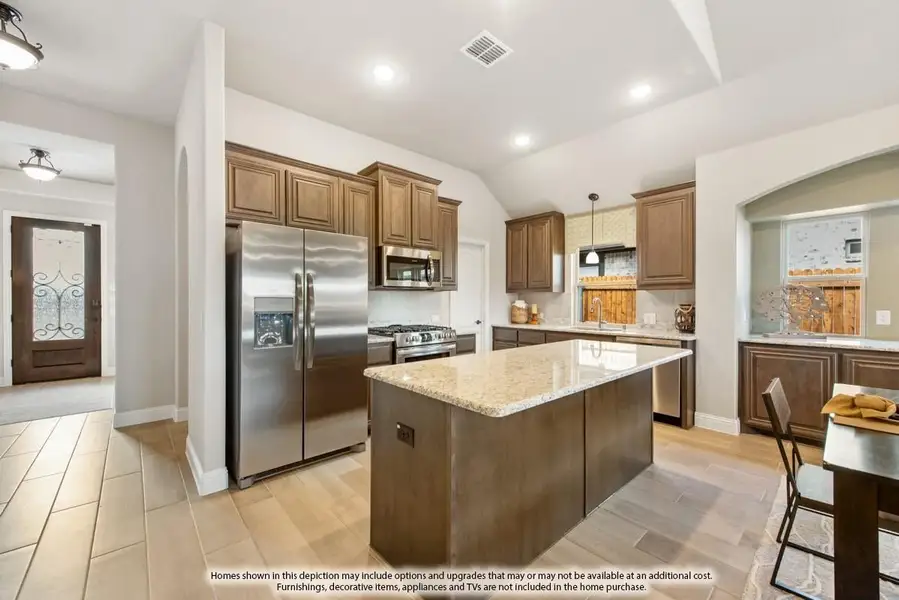 Kitchen with dark wood cabinets, granite island, and stainless steel appliances including refrigerator and gas range