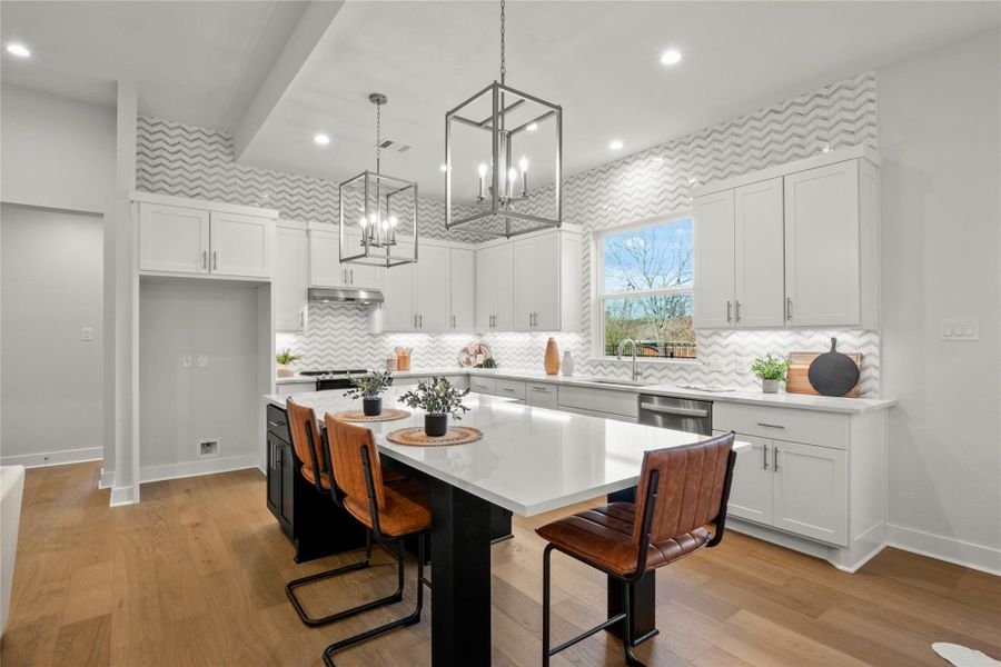 Kitchen with white cabinetry, light countertops, a kitchen island, pendant lighting, and a kitchen breakfast bar Kitchen with white cabinetry, light countertops, a kitchen island, pendant lighting, and a kitchen breakfast bar