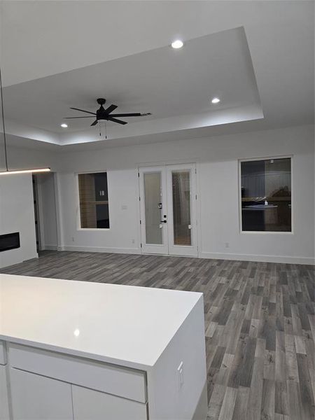 Kitchen featuring wood-type flooring, french doors, a tray ceiling, ceiling fan, and white cabinets