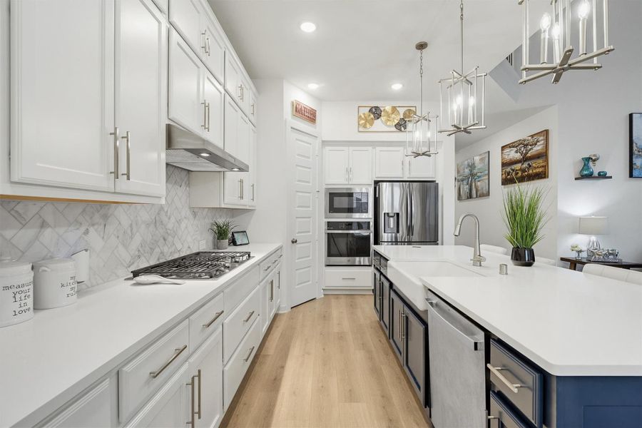 Another view of this gorgeous kitchen highlights the built-in stainless steel appliances, sleek modern backsplash, and a stylish farmhouse sink, showcasing the kitchen’s contemporary design and high end finishes.