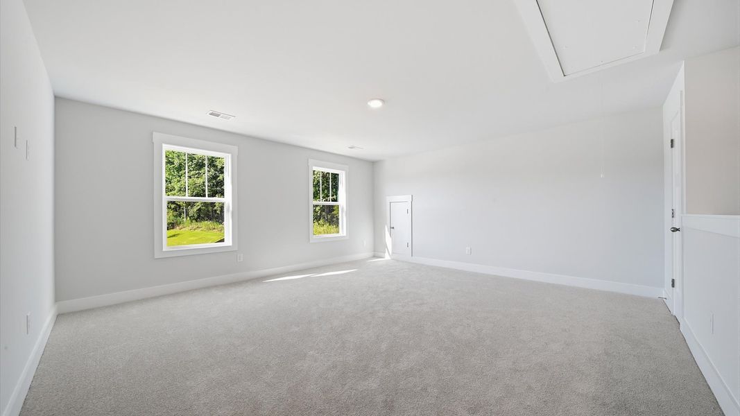 Vibrant carpeted loft offering flexibility as a study nook, game room, or second family space at Creeks at Midway