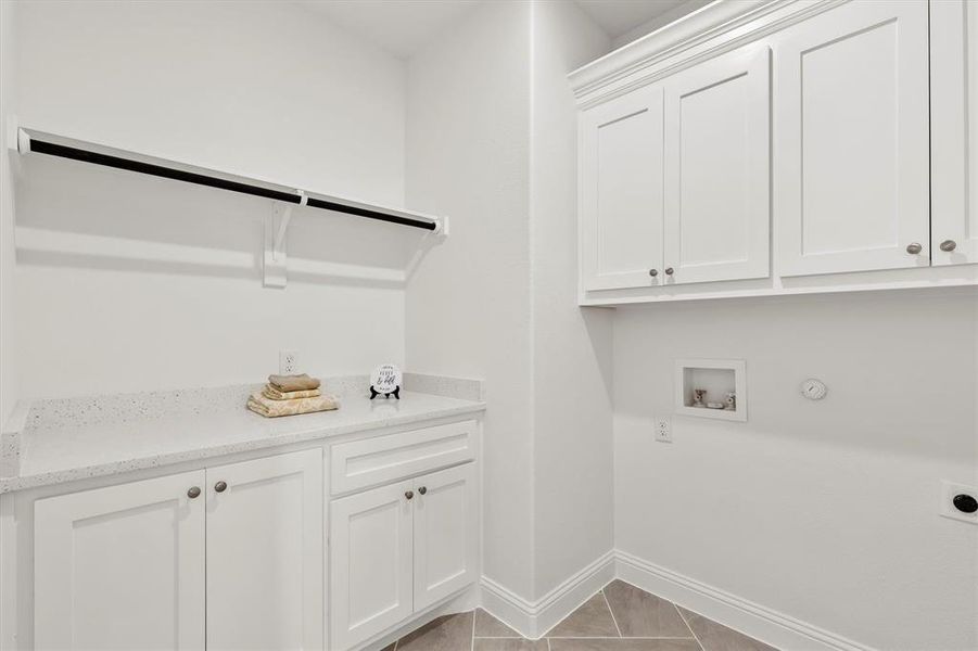 Laundry room with hookup for a gas dryer, hookup for a washing machine, hookup for an electric dryer, light tile patterned flooring, and cabinets