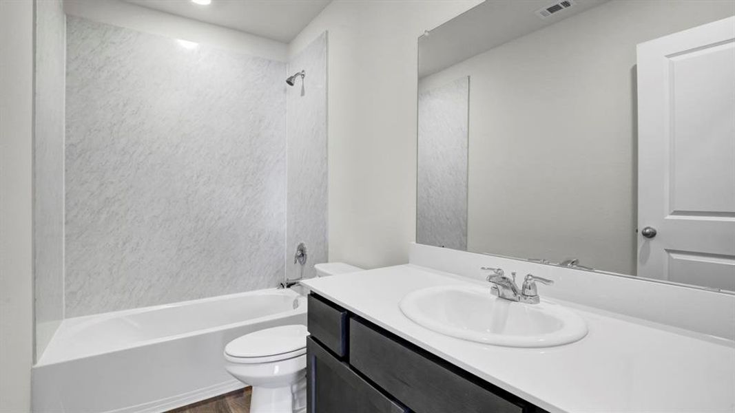 Bathroom with vanity, washtub / shower combination, and dark wood finished floors