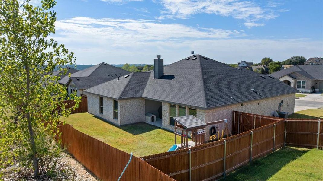 Rear view of house featuring a fenced backyard, a chimney, a patio, brick siding, and roof with shingles
