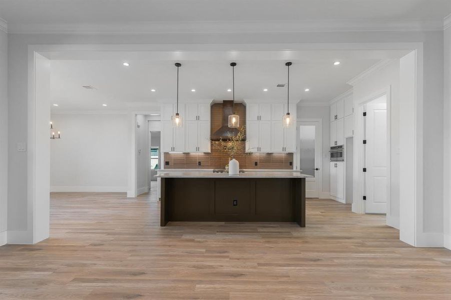 Modern farm kitchen with two tone color scheme, a kitchen island with a farm sink, and pendant lighting.