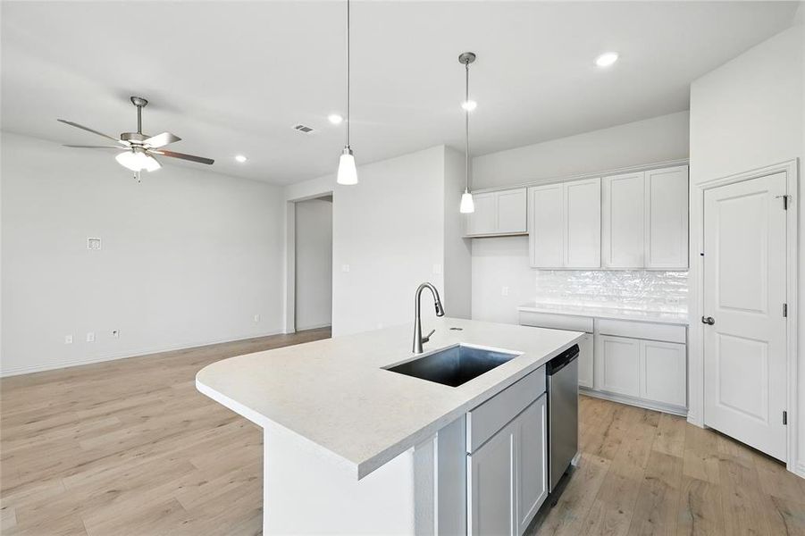Kitchen featuring light wood-type flooring, hanging light fixtures, backsplash, a center island with sink, and recessed lighting Kitchen featuring light wood-type flooring, hanging light fixtures, backsplash, a center island with sink, and recessed lighting