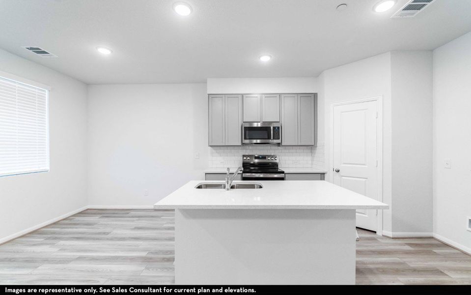 Kitchen featuring light wood-style flooring, gray cabinets, stainless steel appliances, a center island with sink, and recessed lighting