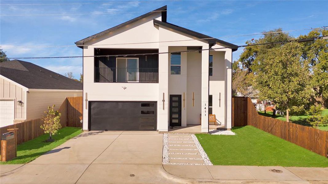 Contemporary home with stucco siding, driveway, a garage, and a balcony