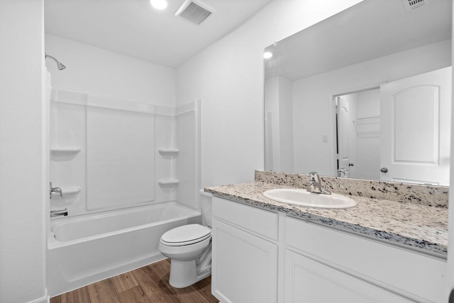 Bathroom featuring vanity, dark wood finished floors, shower / washtub combination, and a spacious closet