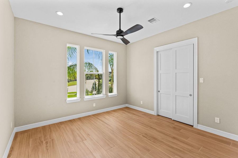 Bright and spacious secondary bedroom featuring large windows, ceiling fan, and neutral finishes.