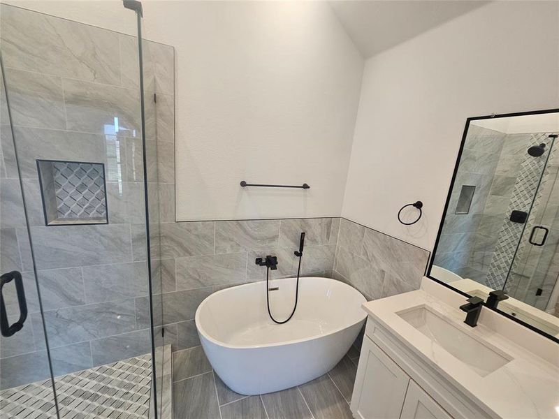 Bathroom with vanity, separate shower and tub, and tile walls
