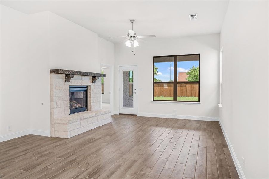 Unfurnished living room featuring a fireplace, wood finished floors, and a ceiling fan Unfurnished living room featuring a fireplace, wood finished floors, and a ceiling fan
