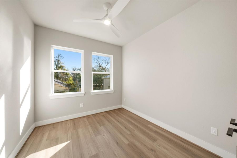 Bright, minimalist room with light wood flooring, neutral walls, and large windows offering natural light.