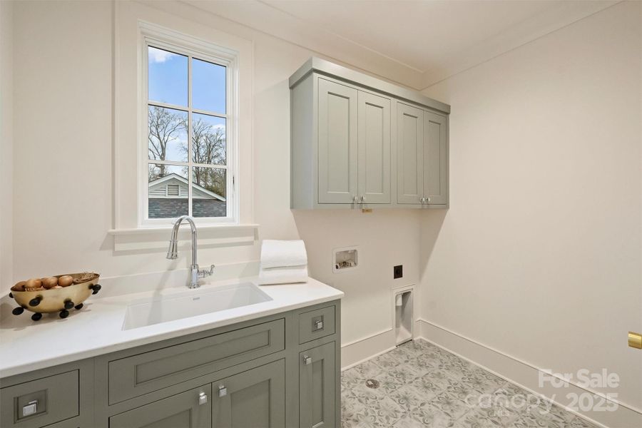 The main laundry room on the second level includes a convenient soaker sink, designer tile selections, and quartz countertops.