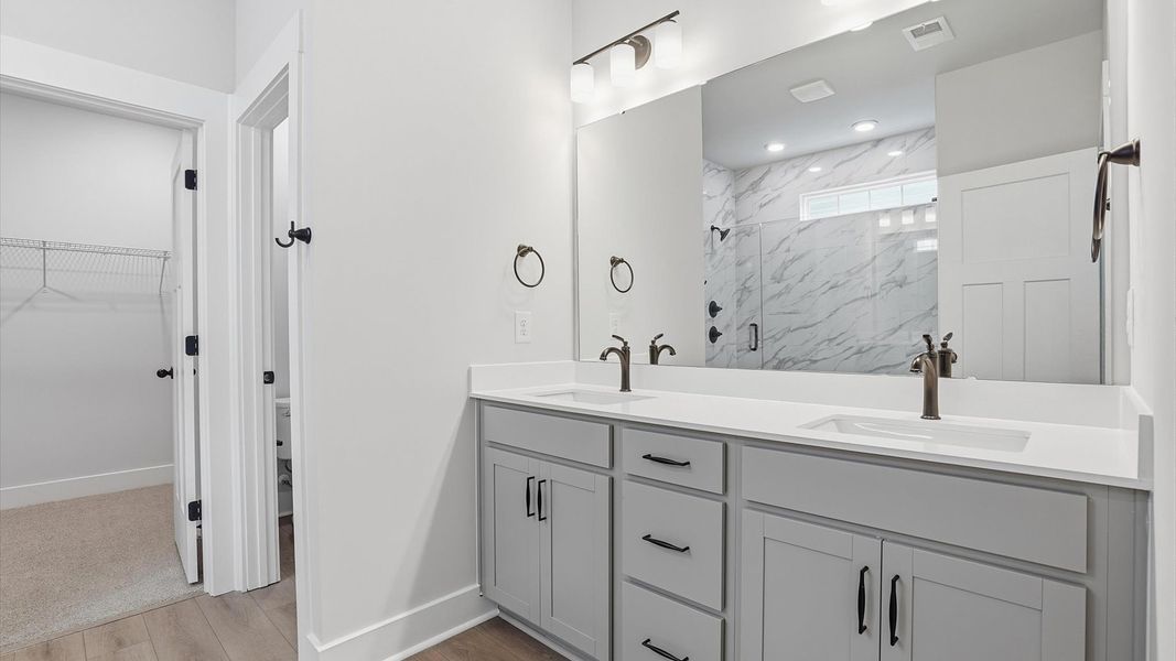 Notable primary bath featuring dual vanity, walk-in shower, and tasteful design touches throughout at Creeks at Midway
