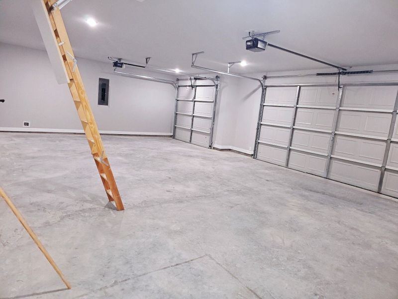 Spacious three-car garage with an access ladder to the spacious attic.