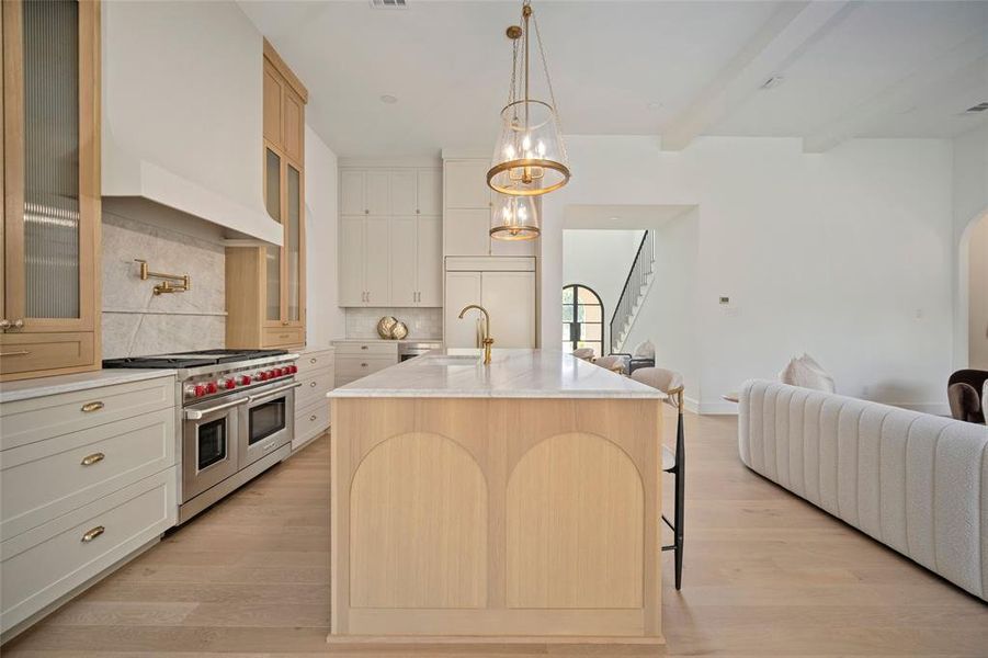 Kitchen featuring range with two ovens, backsplash, light wood finished floors, glass insert cabinets, and beamed ceiling