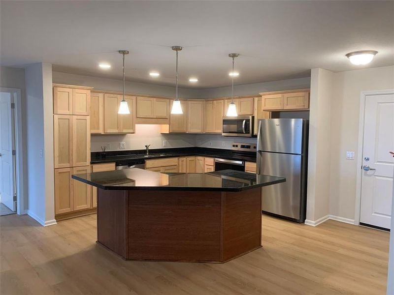 Kitchen featuring appliances with stainless steel finishes, light brown cabinets, recessed lighting, pendant lighting, and a center island