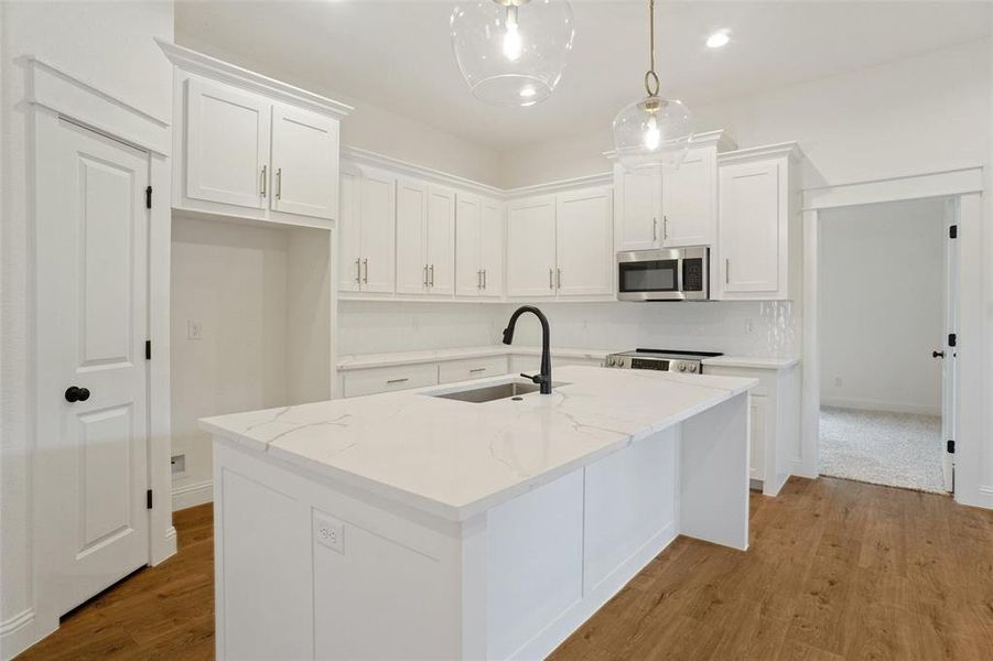Kitchen with light wood-style flooring, white cabinetry, stainless steel appliances, recessed lighting, and light stone countertops