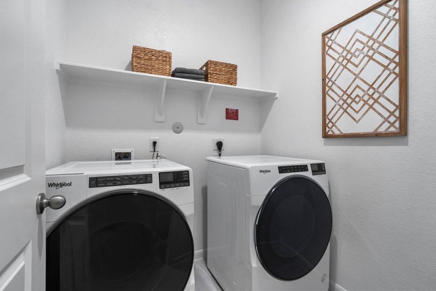 A dedicated laundry space complete with a modern Whirlpool washer and dryer set, upper shelving for storage, and a bright, clean aesthetic, making household chores a breeze.