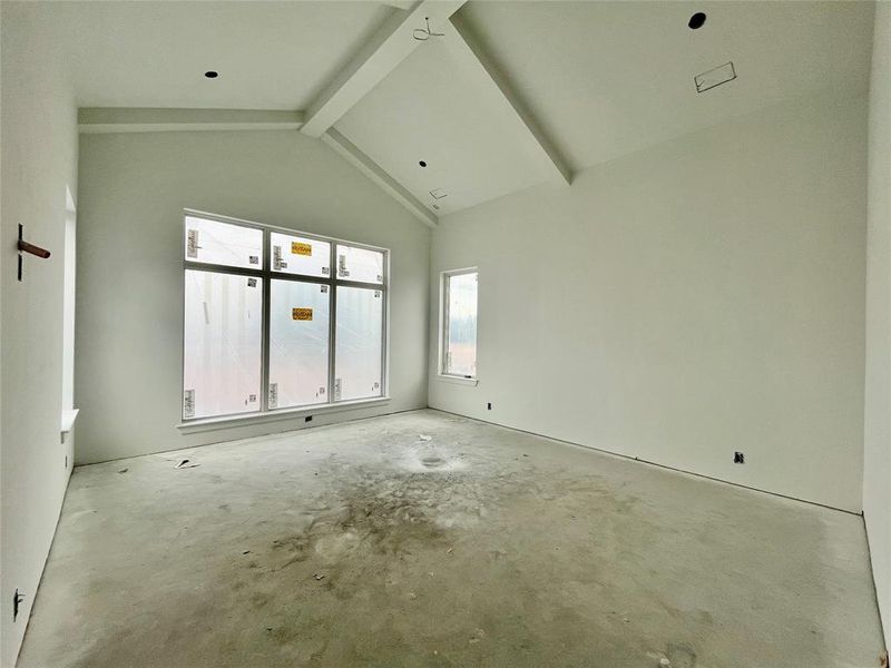 Unfurnished room with beamed ceiling and high vaulted ceiling